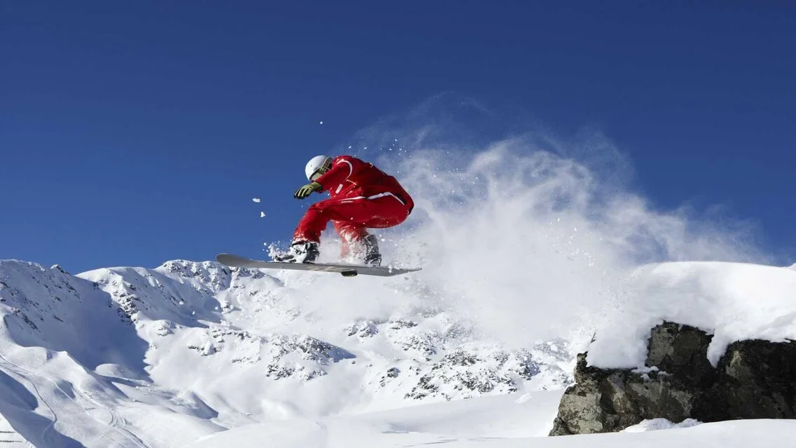 Snowboarder springt Fun auf dem Snowboard in Fiss im Winter